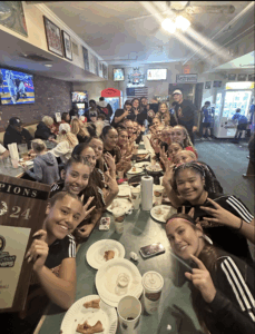 Soccer team posing with menu at tables